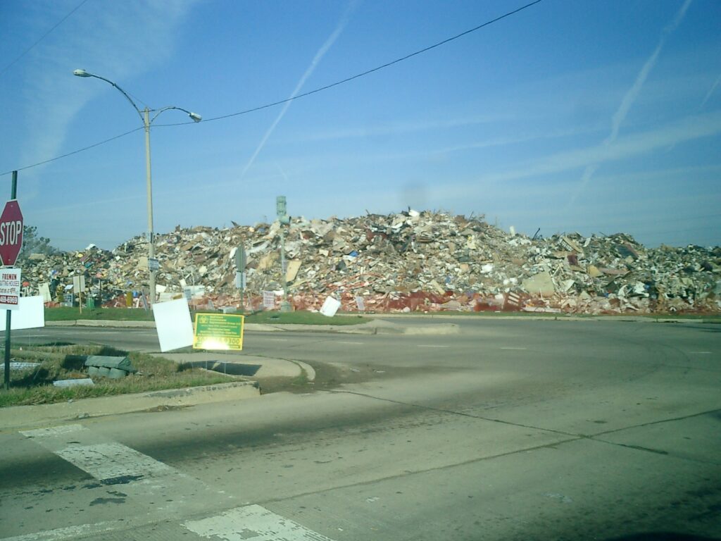 Massive pile of post-Katrina debris stacked along West End Boulevard in Lakeview, New Orleans, including appliances, wood, and sheetrock from damaged homes.